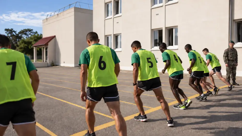 AI-generated illustration of candidates running the 20-metre Luc Léger shuttle test outside a selection building in Aubagne, watched by a Foreign Legion instructor in a green beret